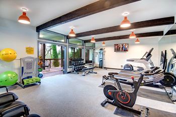the gym has plenty of equipment and glass doors to the patio